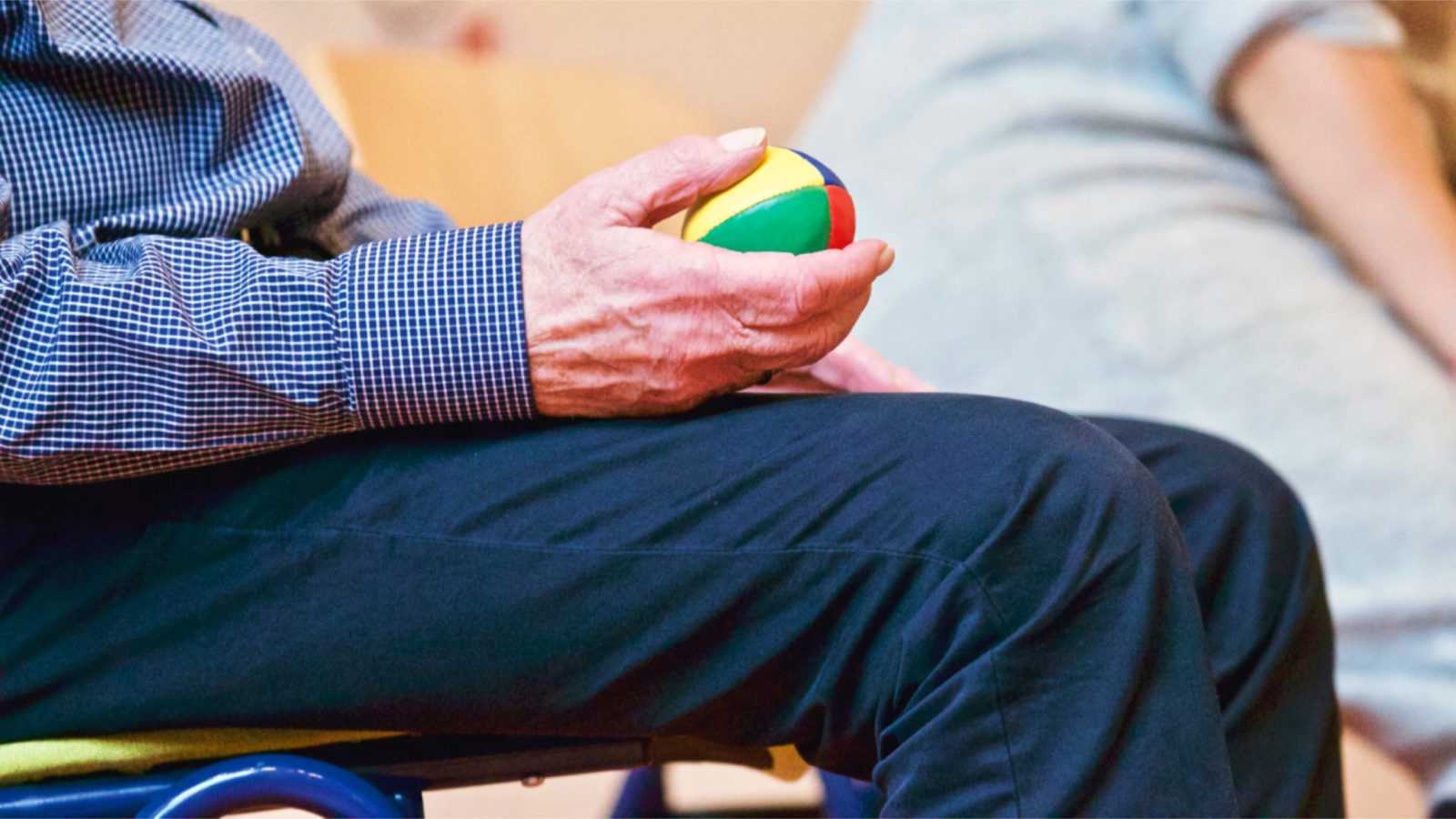 older person holding ball toy
